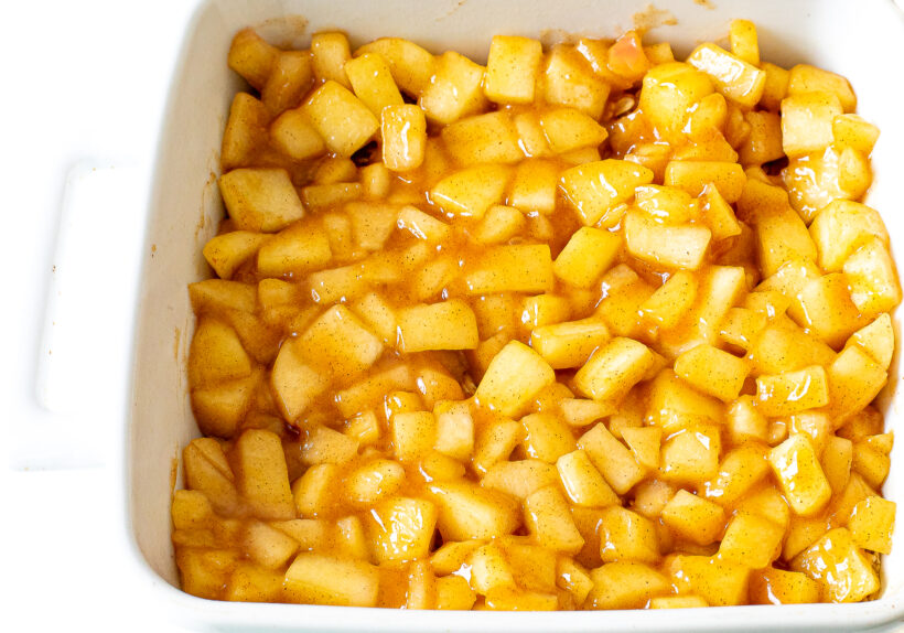 Apple filling spread into white baking pan.