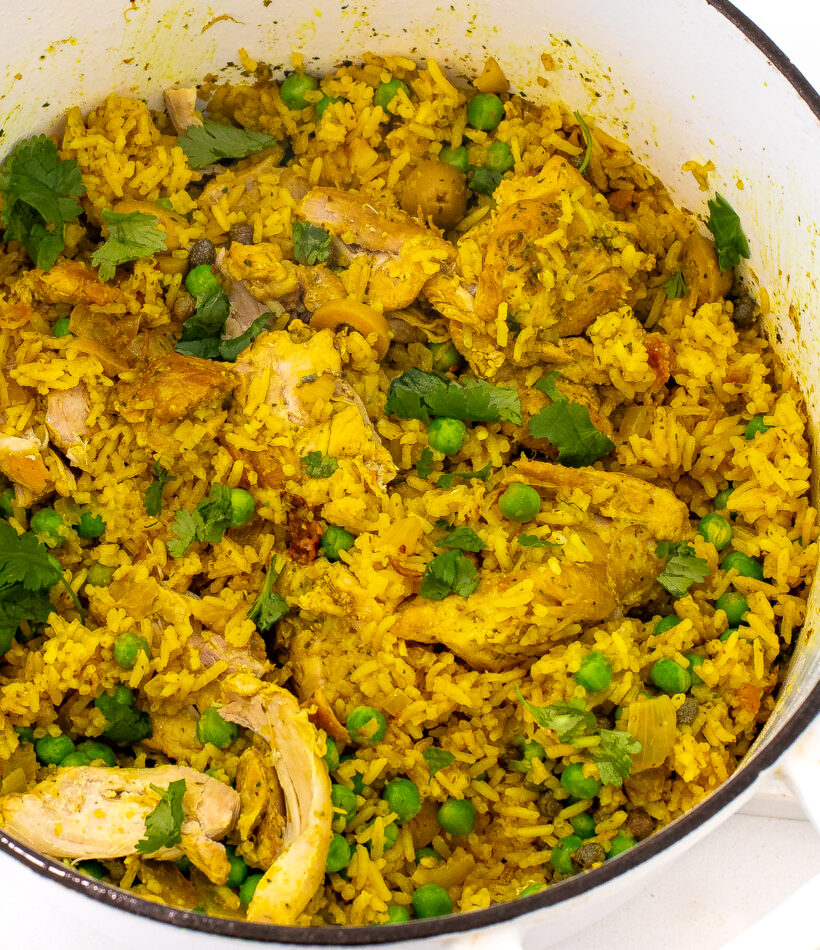 Chicken and rice in a pot with peas and cilantro.