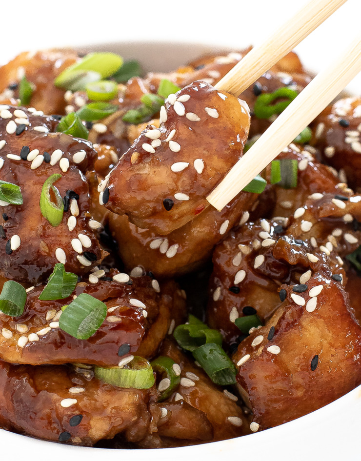 author picking up asian chicken bite with wooden chopsticks
