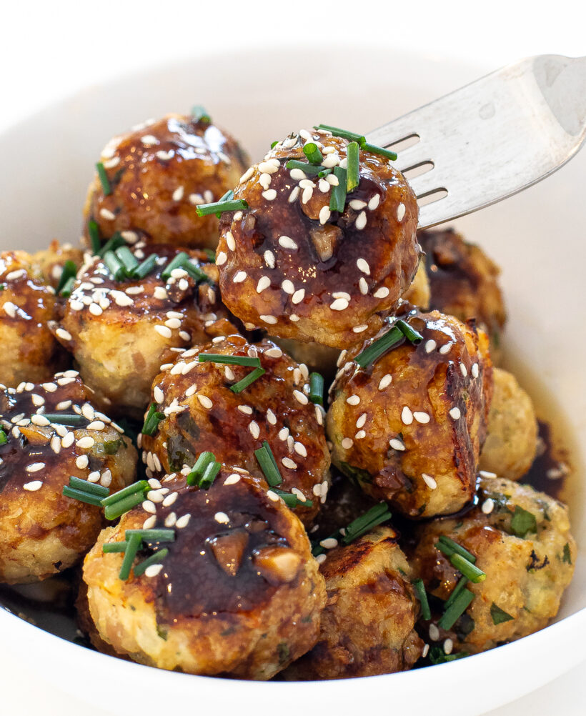 chicken meatballs in bowl with sesame seeds and green onions