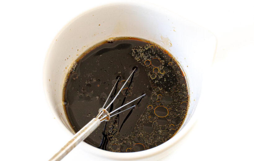 whisking sauce for Szechuan beef in small white bowl