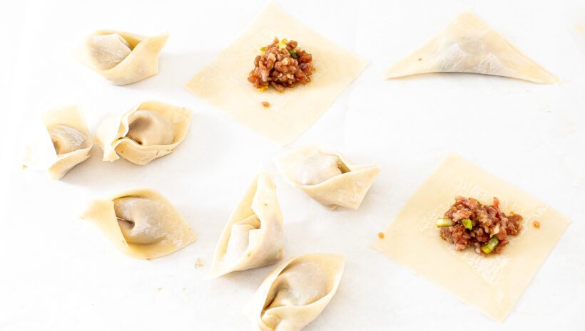 Wonton wrappers filled with filling and folded.