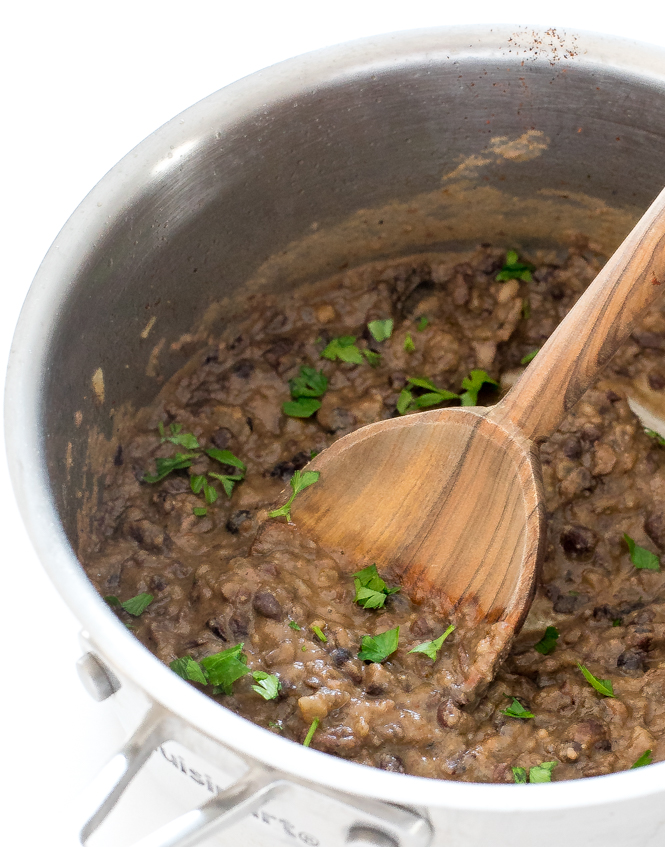 Easy Refried Black Beans | chefsavvy.com side shot of refried beans in saucepan topped with chopped cilantro