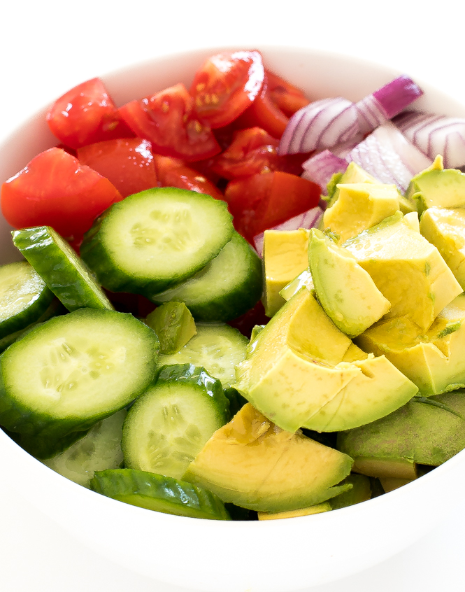 red onion, cubed tomatoes, sliced cucumbers and cubed avocado in bowl