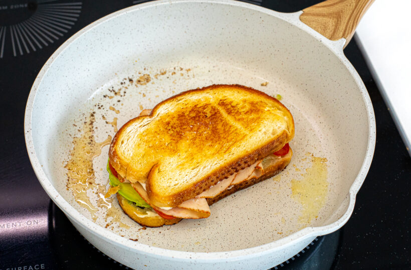 The two sliced of bread put together in the pan to make a sandwich. 