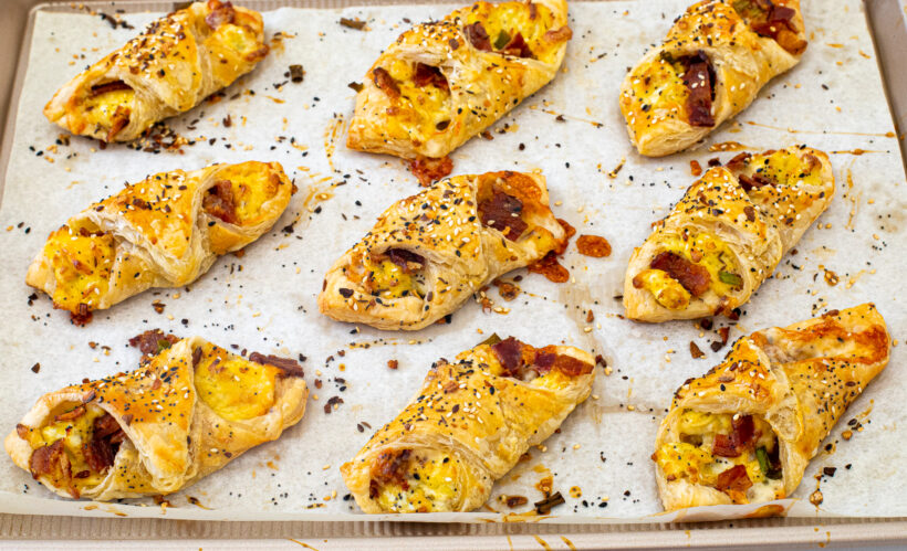 Baked bacon egg and cheese pastries on a baking sheet.
