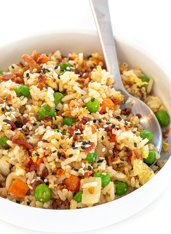 Bacon fried rice in a white bowl with a silver spoon. 