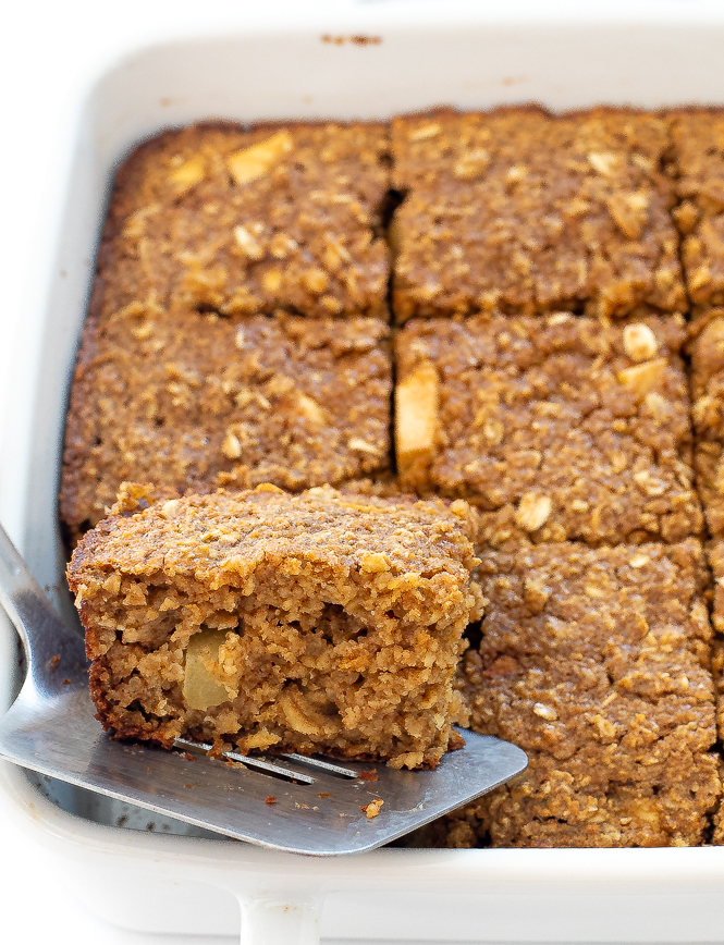 Spatula lifting a slice of Baked Apple Oatmeal from a white casserole dish.
