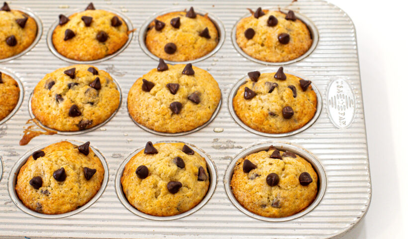 Banana chocolate chip muffins in a muffin tin after being baked.