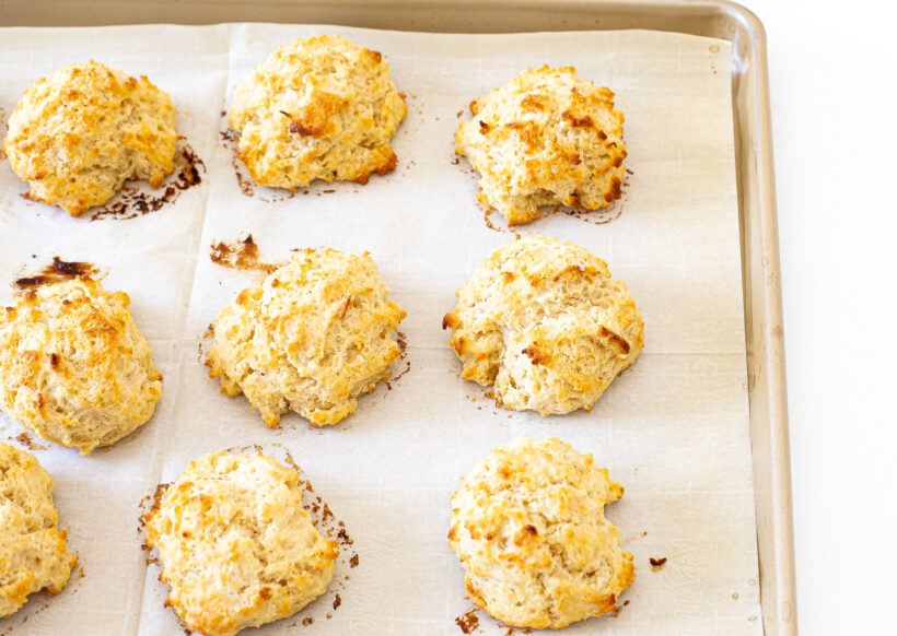 5 ingredient drop biscuits lined up on a baking sheet after being baked. 