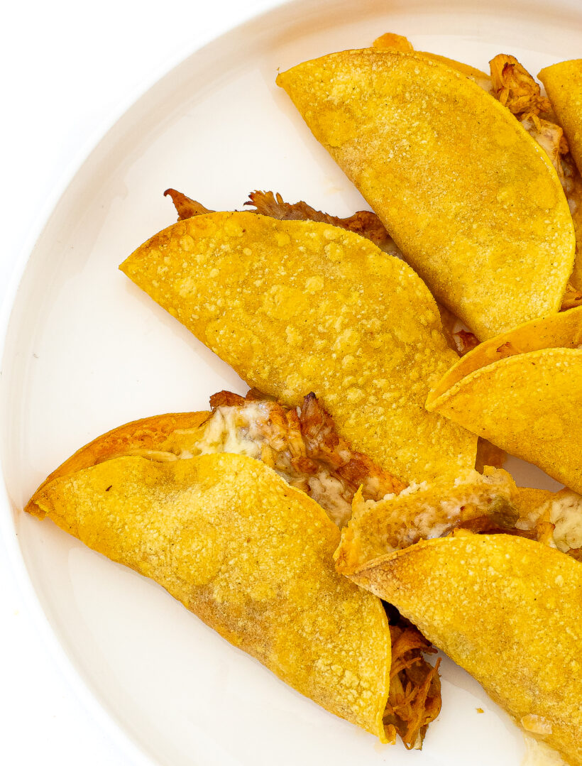 Crispy Baked Chicken Tacos placed on a white plate.