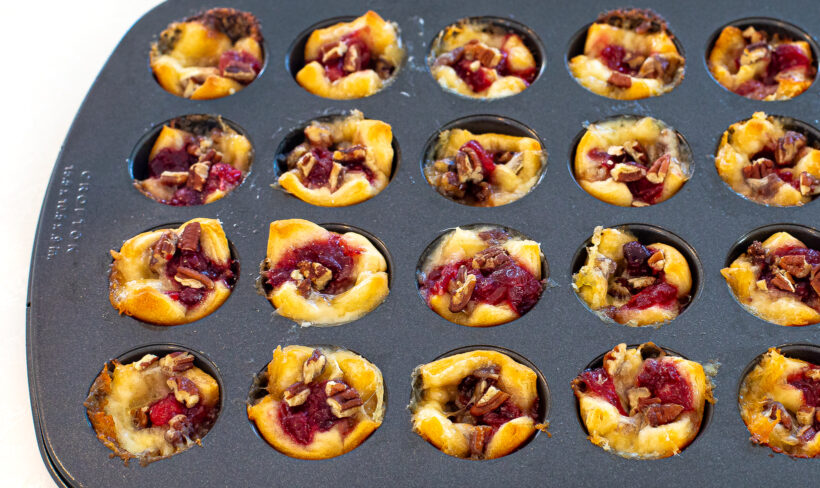 Muffin tin filled with cranberry brie bites after being baked. 