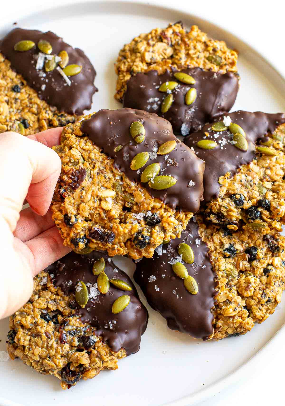 crisp granola cookies dipped in chocolate and sprinkled with sea salt and pepitas
