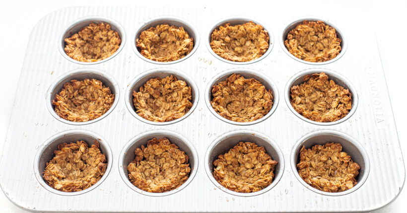 Granola cups in a muffin tin after being baked.