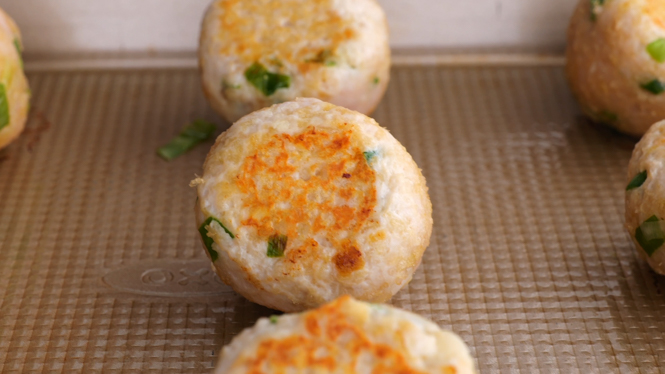 Meatballs being cooked on a baking sheet in the oven. 
