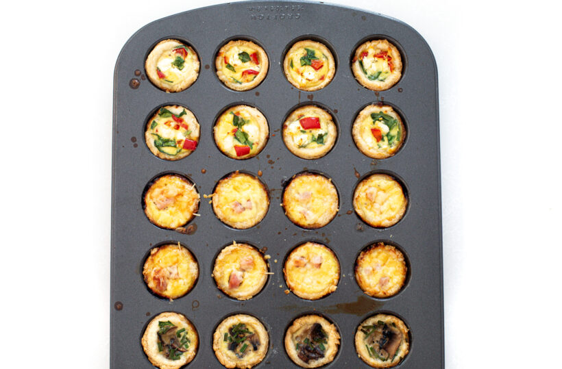 Mini quiches in a muffin tin after being baked.
