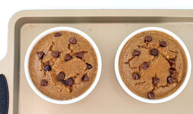 Two ramekins of baked oats on a sheet pan after being baked. 