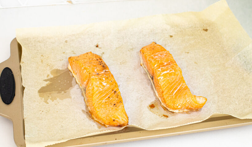Raw salmon laid out on a baking sheet lined with parchment paper.