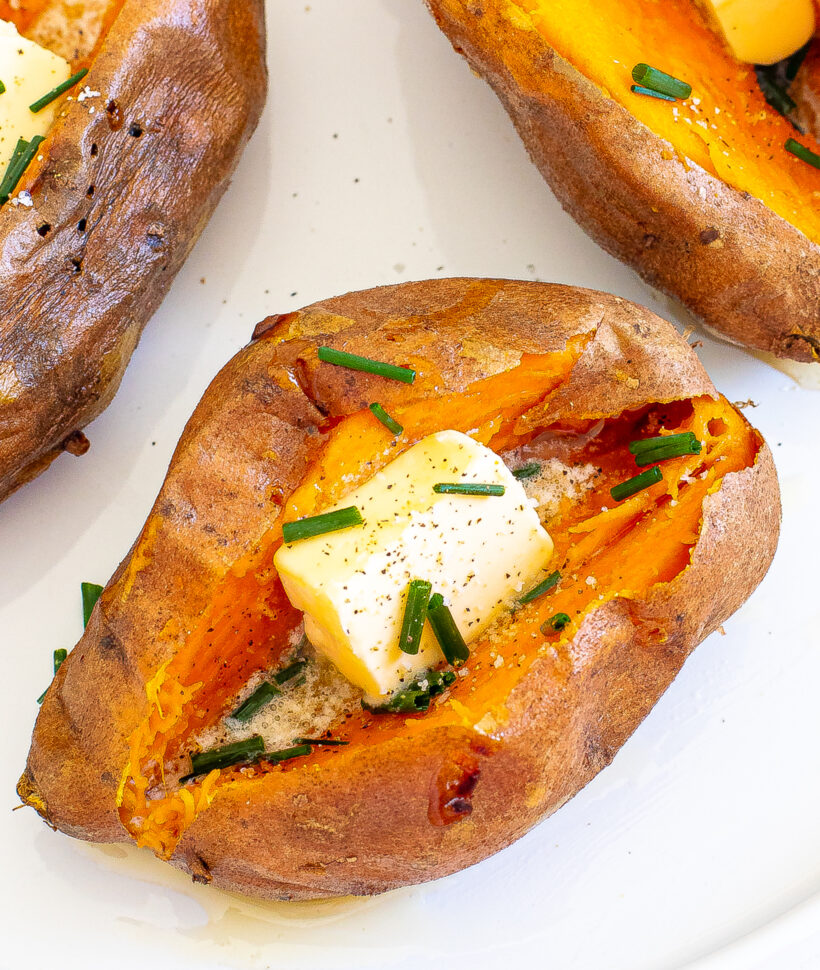 Overhead shot of a baked sweet potato with a square of butter and chives on top.