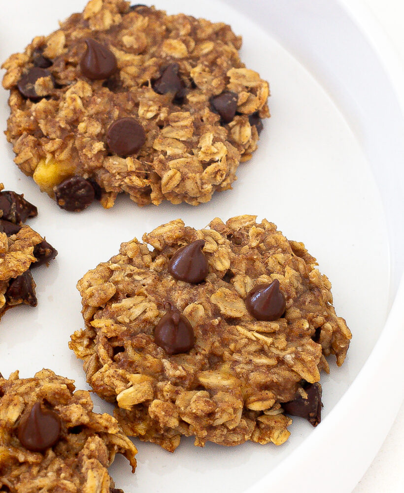 Banana oatmeal cookies topped with chocolate chips and served on a white plate. 