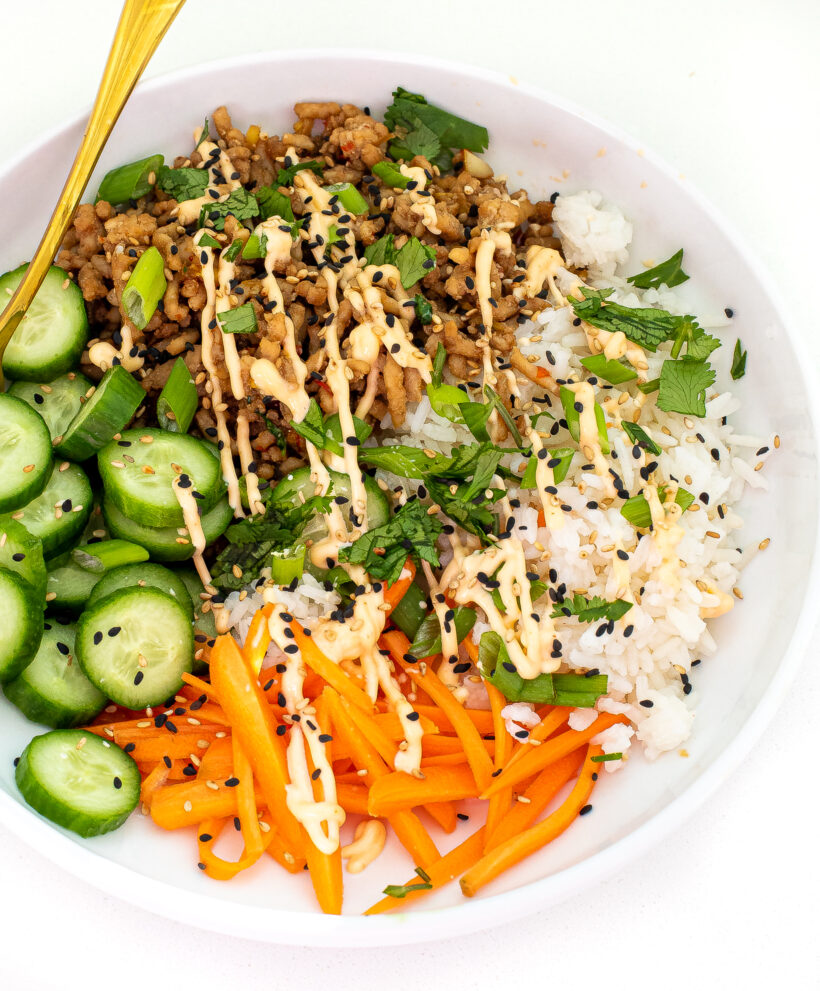 Banh mi bowl assembled in a white bowl with a drizzle of spicy mayo on top. 