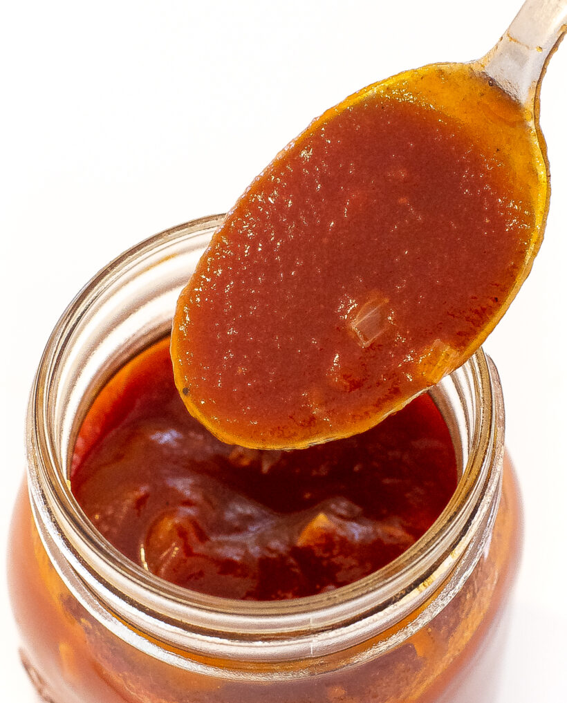 scooping bourbon barbecue sauce out of glass mason jar