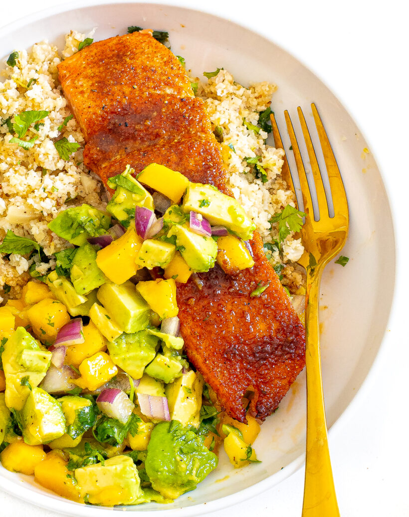 Salmon on a bed of cauliflower rice topped with mango avocado salsa.