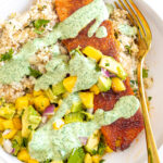 Salmon with rice and mango salsa topped with cilantro sauce drizzle.