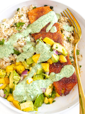 Salmon with rice and mango salsa topped with cilantro sauce drizzle.