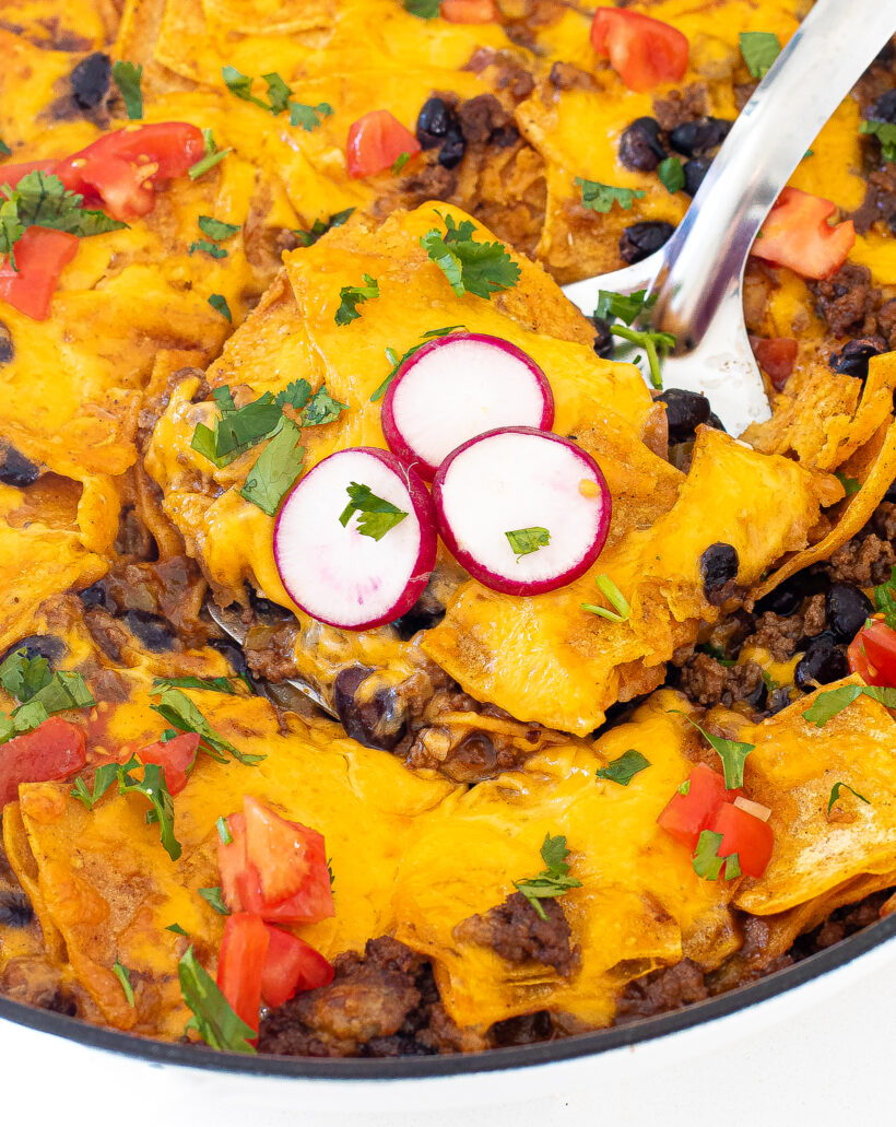 Beef enchilada skillet sliced into squares with a spatula picking up a piece. 