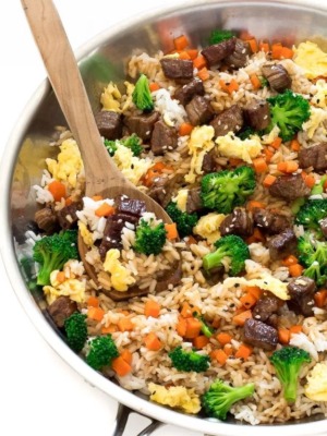 beef fried rice in pan with wooden spoon and veggies