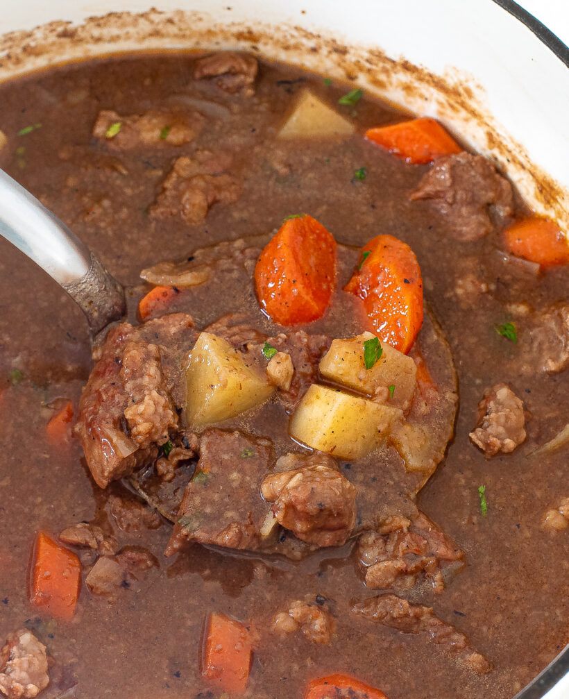 beef stew in cast iron pot with carrots and potatoes