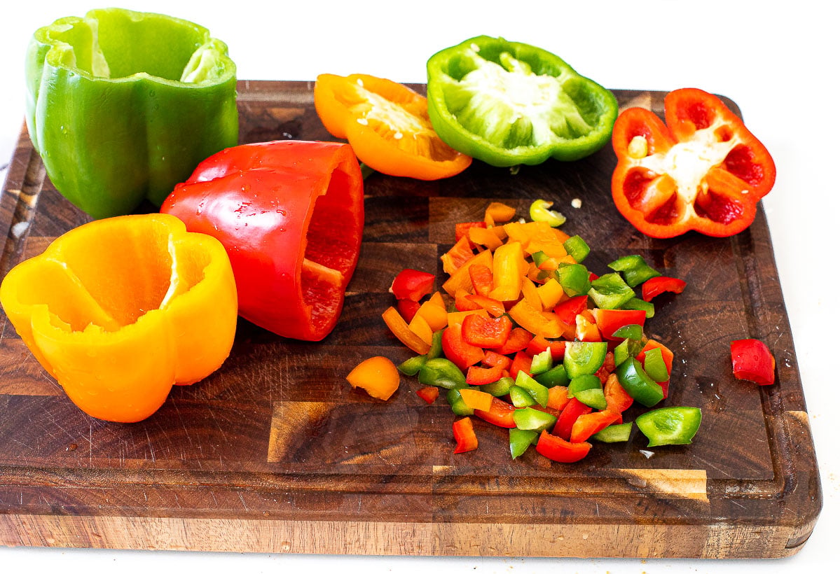 cutting orange, green and red bell peppers on a cutting board