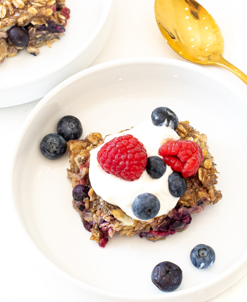 Overhead shot of portion of berry baked oatmeal topped with yogurt and fresh berries.