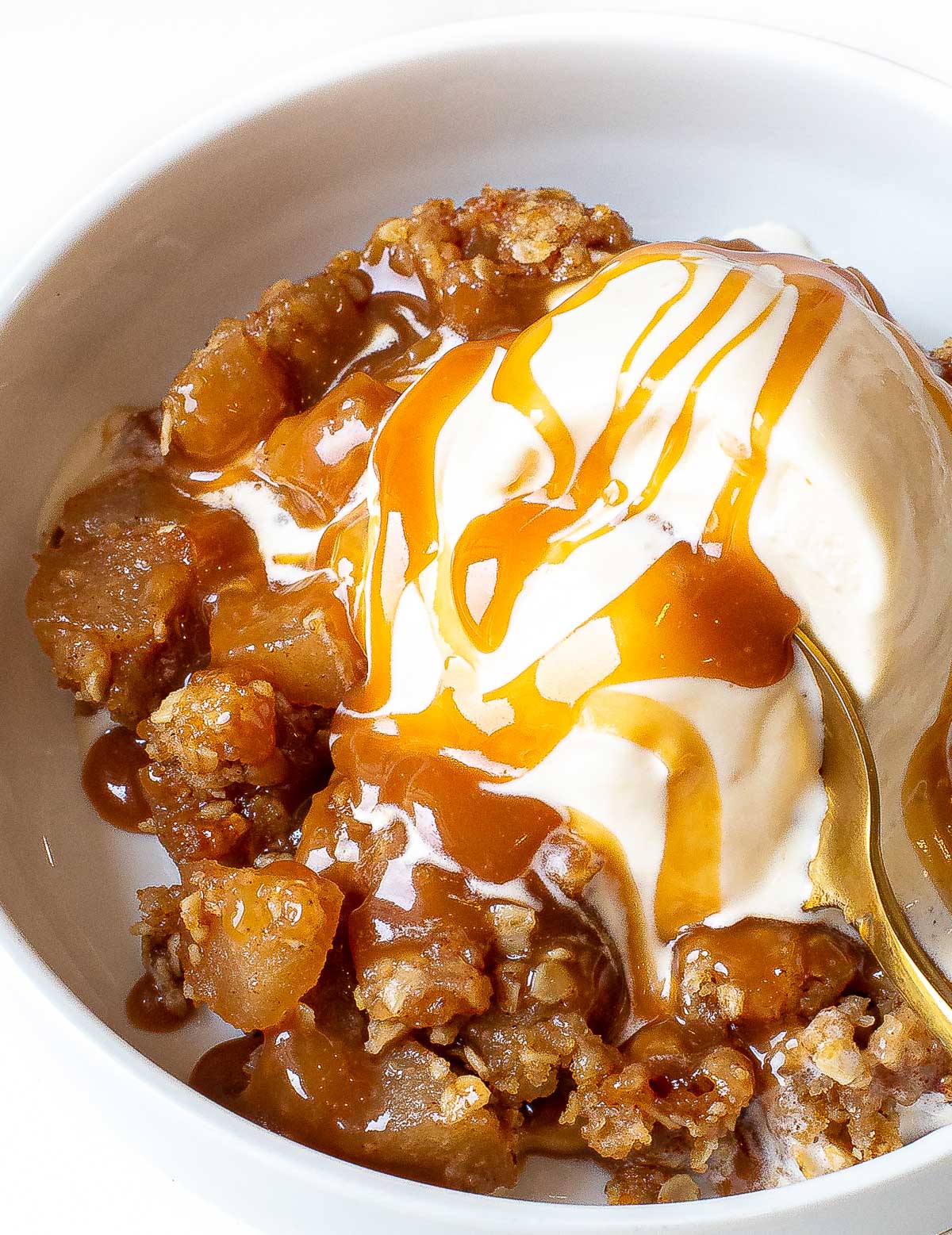 Apple crisp served with a scoop of vanilla ice cream and caramel drizzle.
