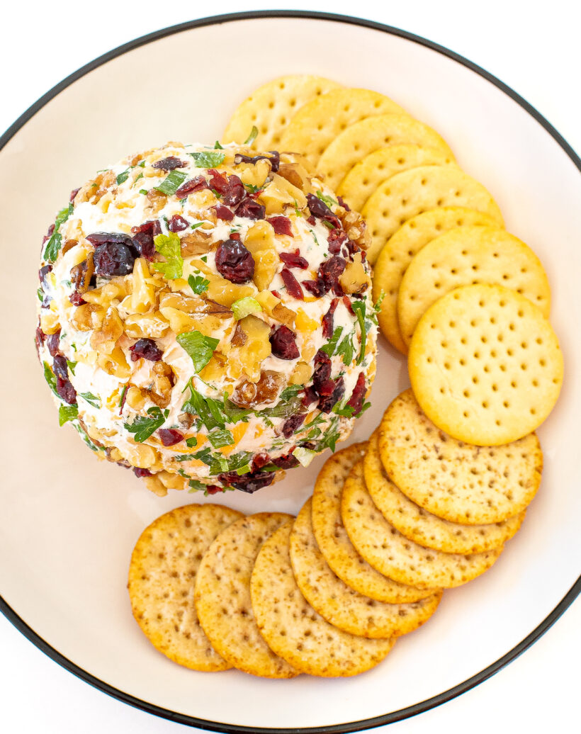 A top down view of a cheeseball on a plate with crackers.