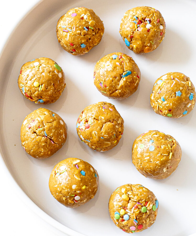 Overhead shot of birthday cake energy balls on a white plate.