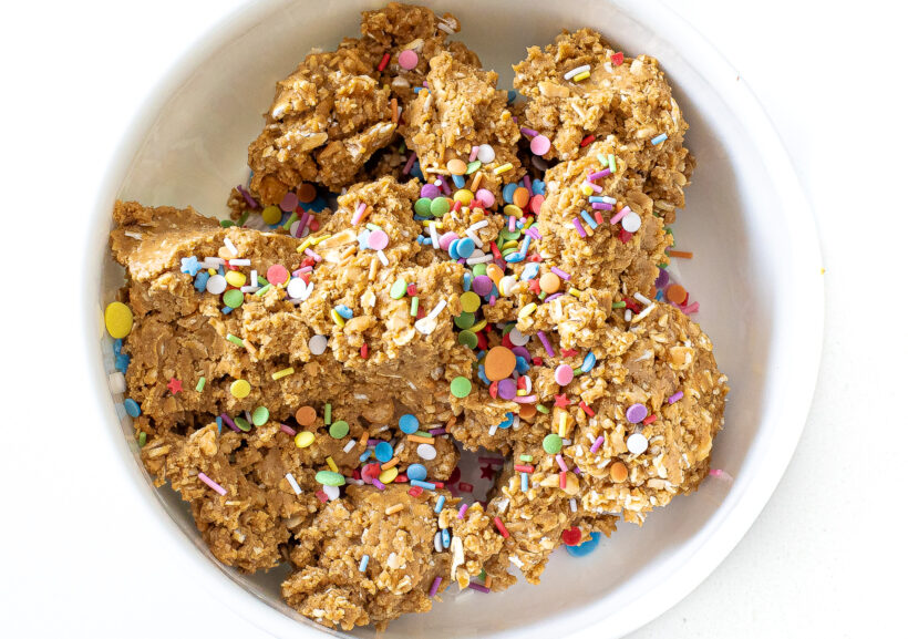 Energy bite mixture in a bowl with rainbow sprinkles poured on top. 