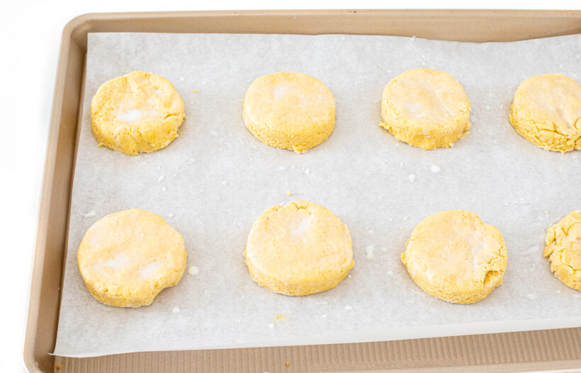 Buttermilk biscuit dough cut into circles and placed on a baking sheet.