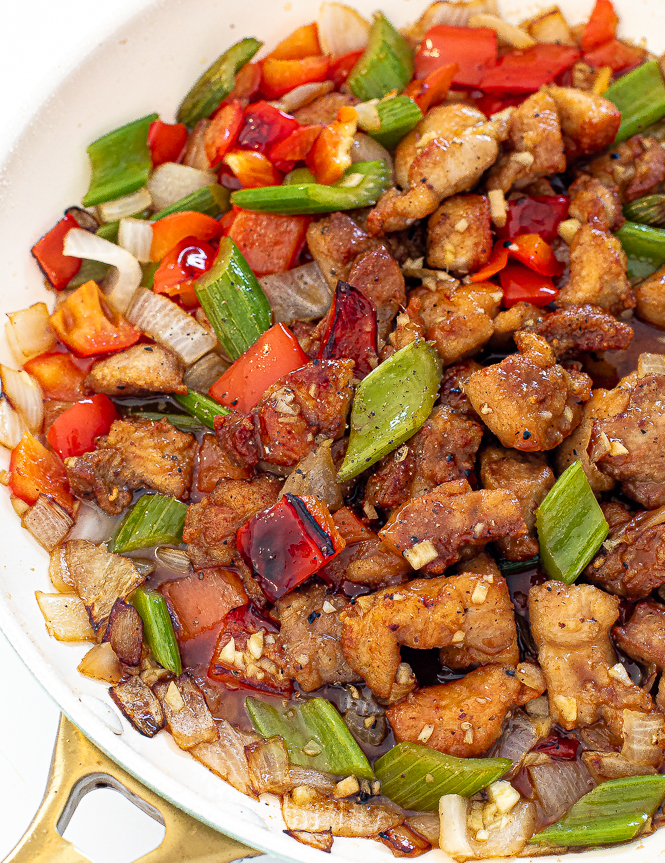 Black pepper chicken in a white wok.