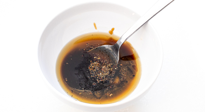 Mixing a brown sauce in a white bowl with a white spoon.