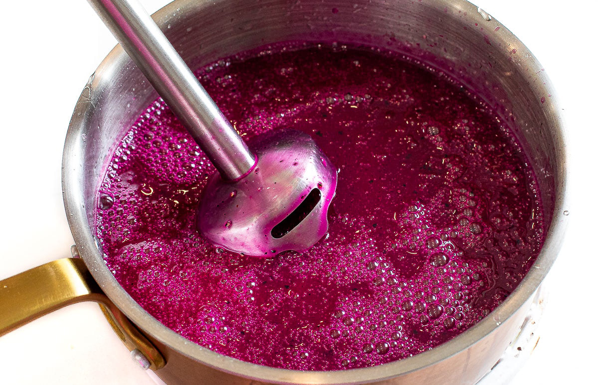 Blending dragon fruit mixture with an immersion blender.