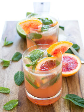 two blood orange mojitos on a wooden cutting board with fresh mint and slices or blood oranges | chefsavvy.com