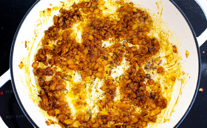 Sauted onions with crushed tomatoes added in a large skillet.