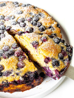 Blueberry cake with a cake spatula holding a slice.