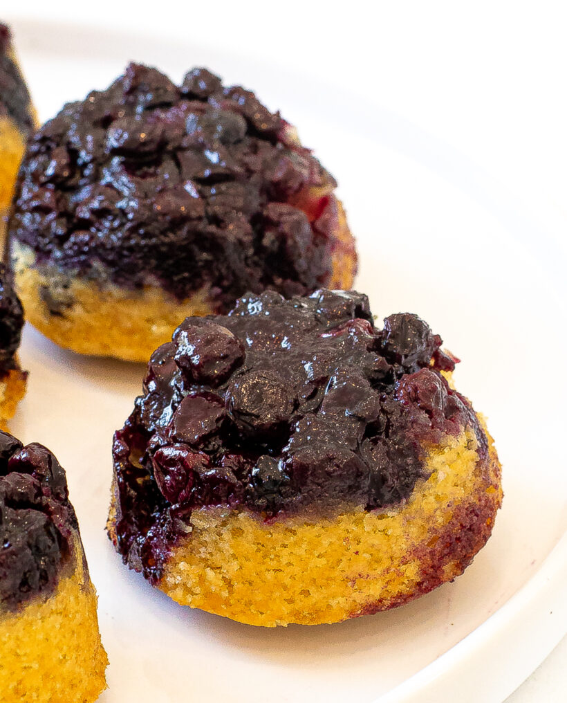 Mini blueberry upside down cake inverted onto a plate to show the blueberry layer on top. 