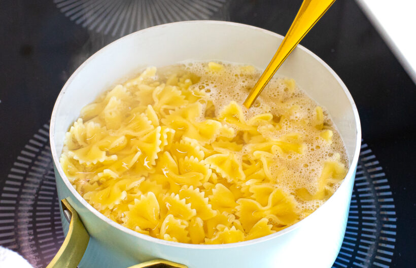 Bowtie pasta boiling in a large pot of pasta on the stove. 
