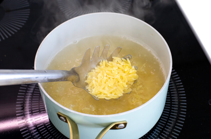 Orzo cooking in a pot of water. 
