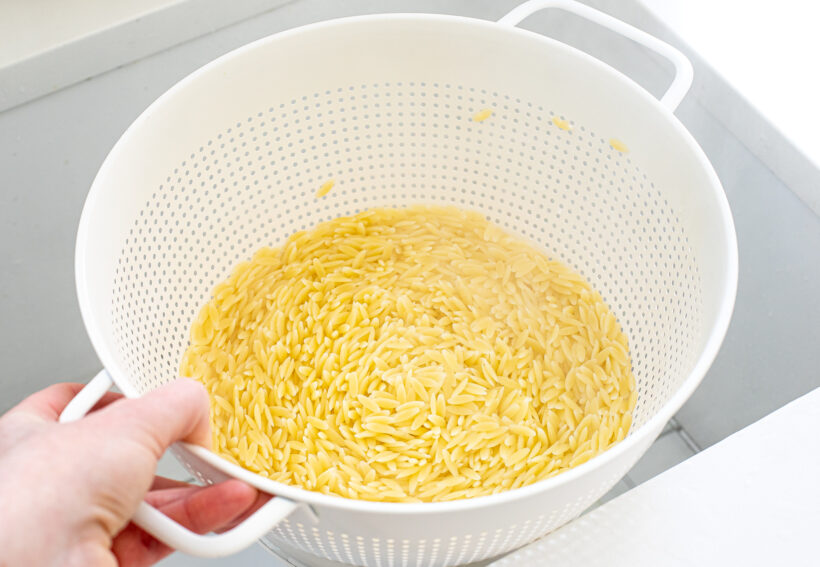 Orzo being drained in a colander. 