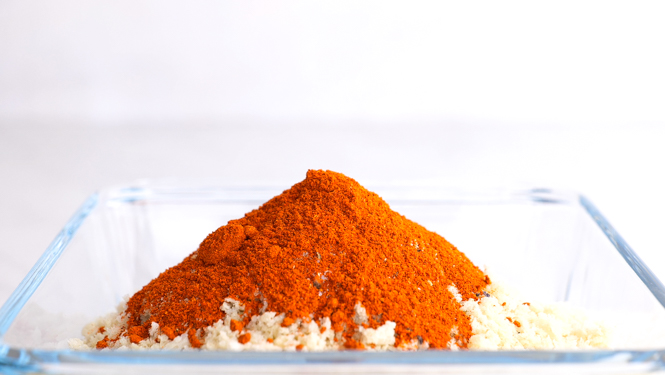 adding breading ingredients for chicken in a clear glass dish